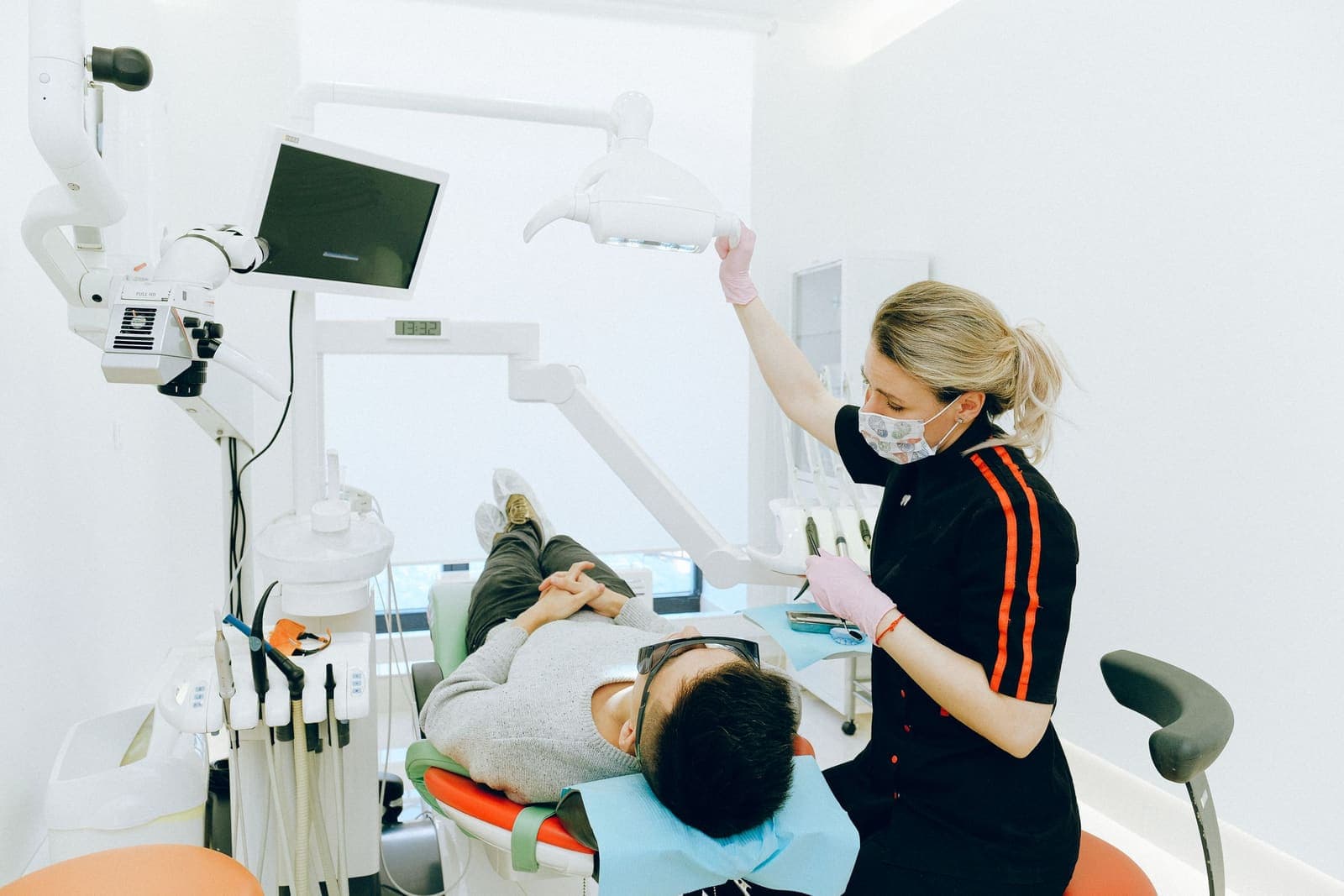 A patient receives a dental check-up while the clinician inspects the upper arch.