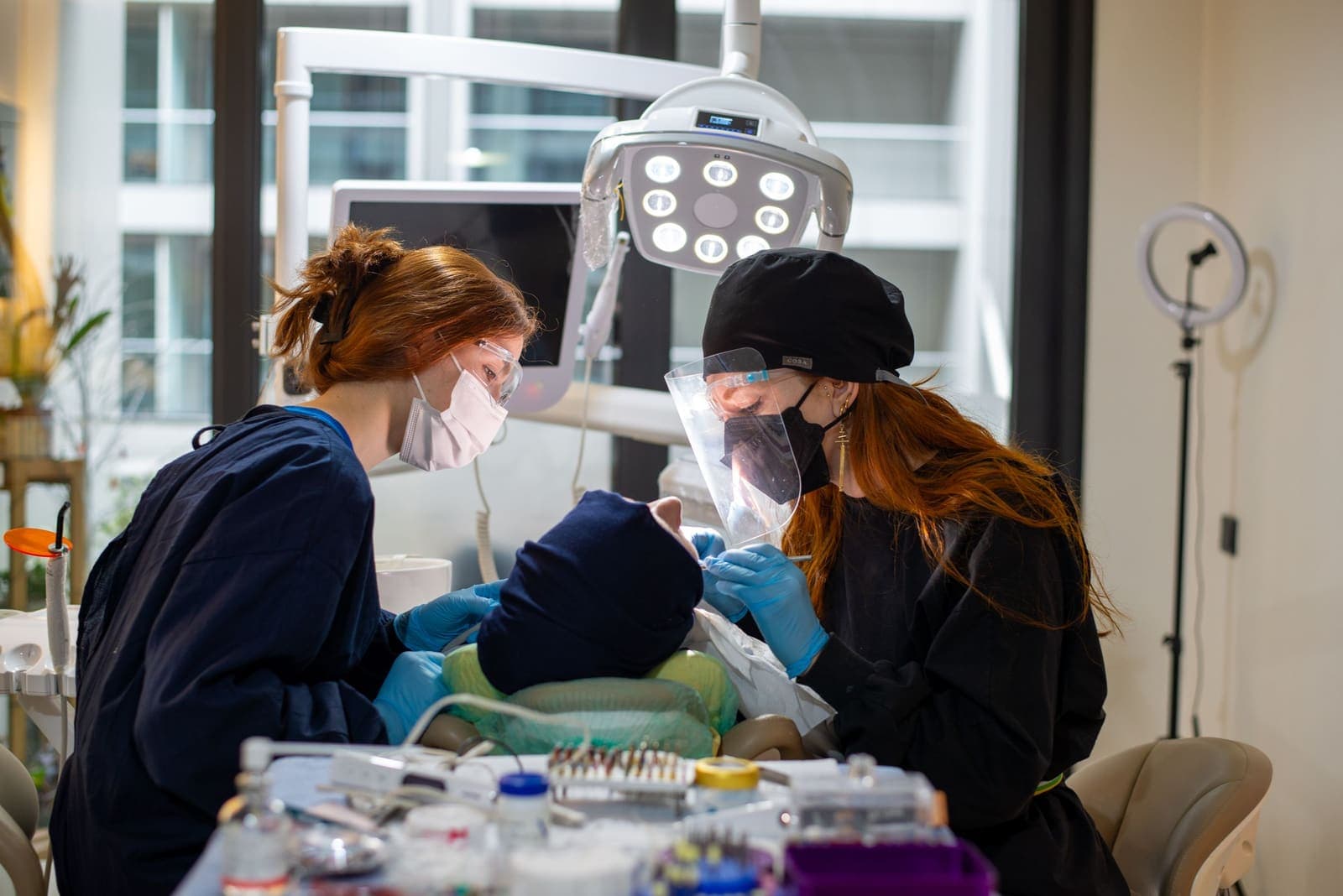 A dental team examines a patient together in a clinic operatory.