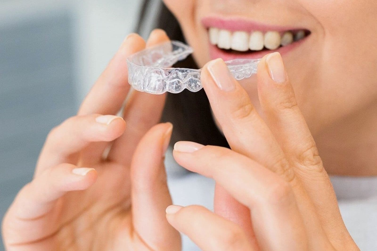A smiling adult wears a clear dental aligner.