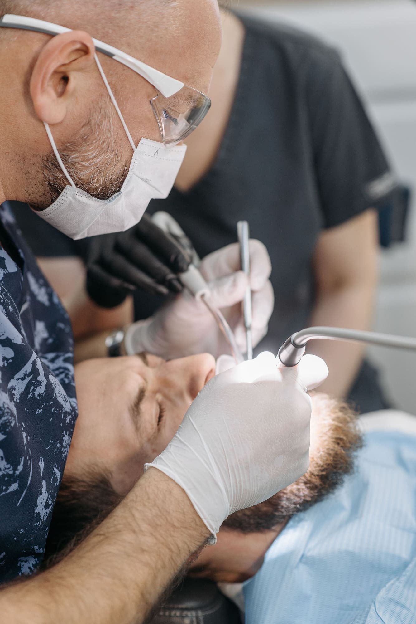 A dentist examines a patient's teeth closely during a clinical appointment.