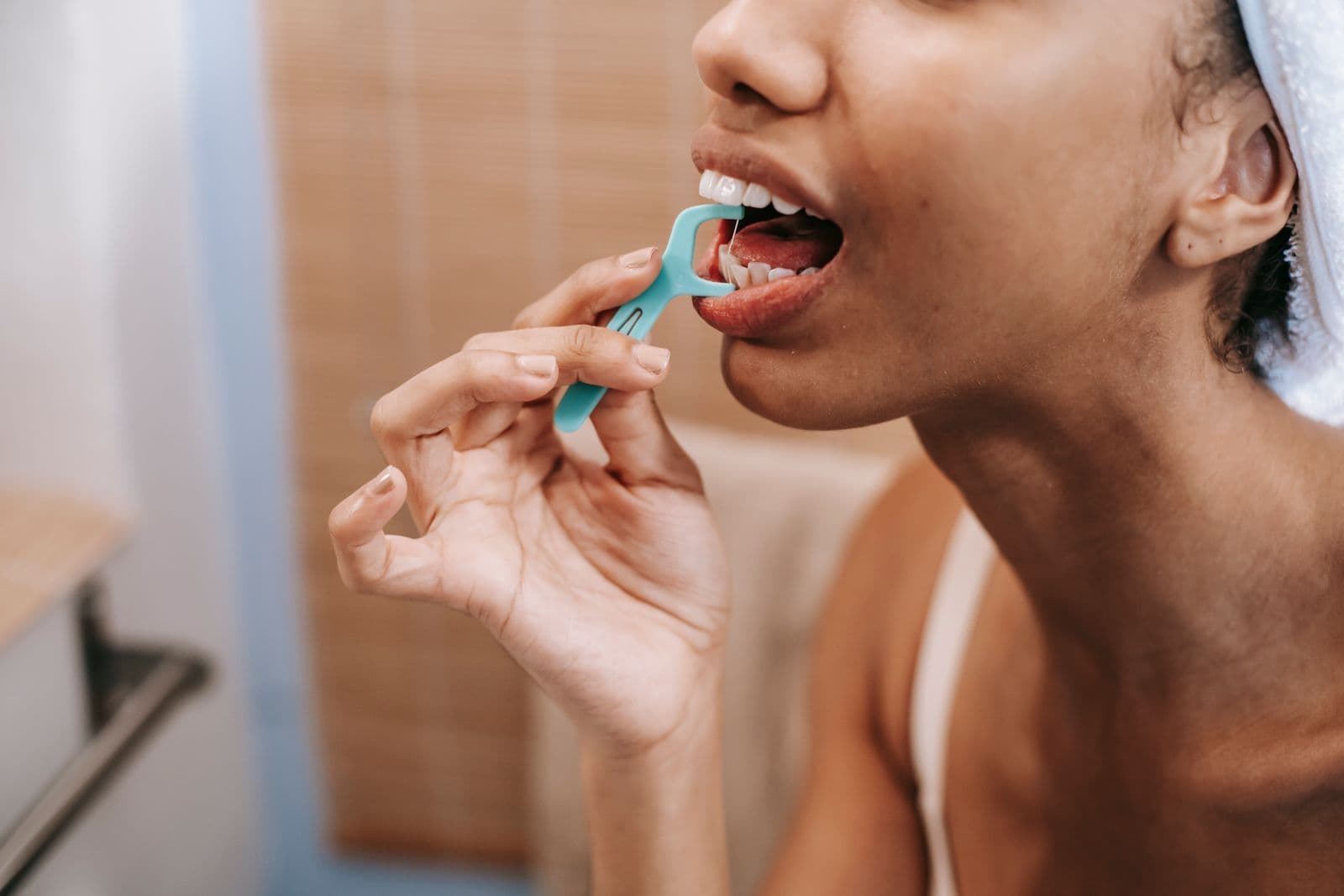 A woman uses a dental floss pick to clean between her teeth.