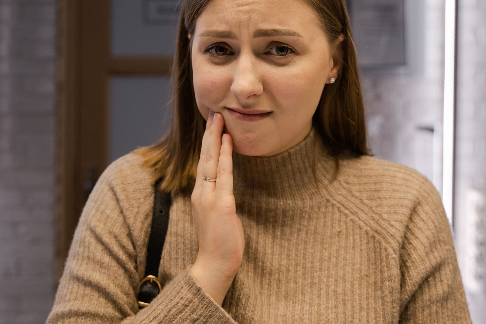 A patient in discomfort from a toothache sits in a dental clinic.