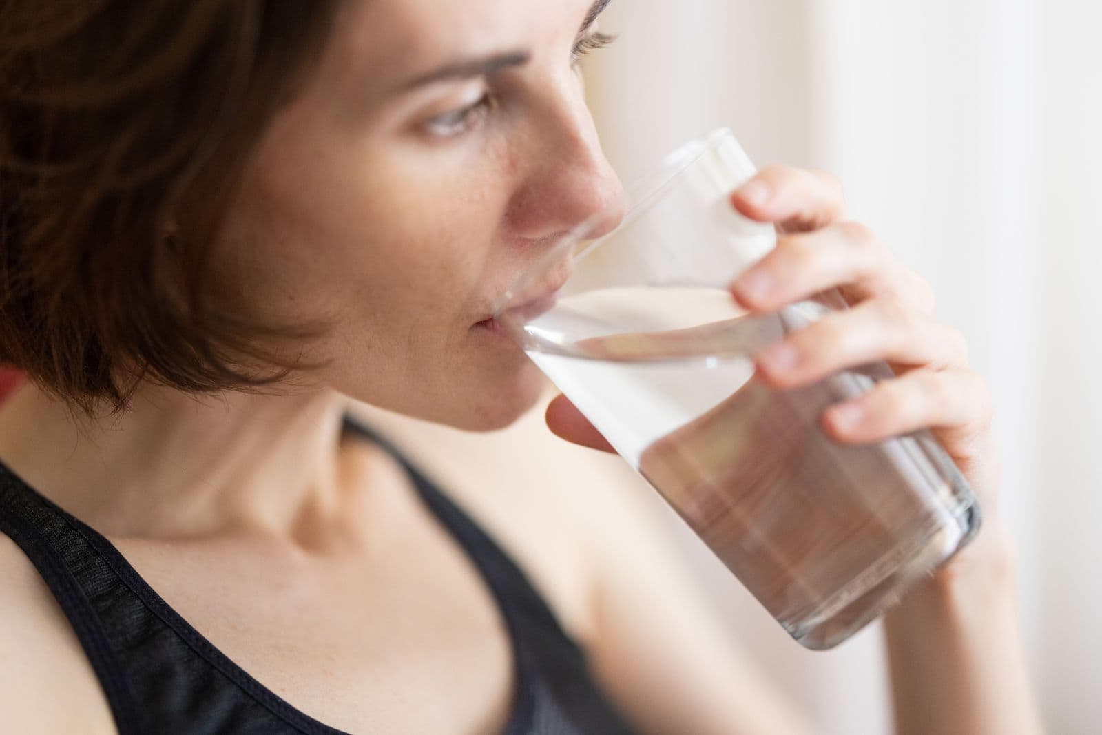 A woman drinks from a glass of water.